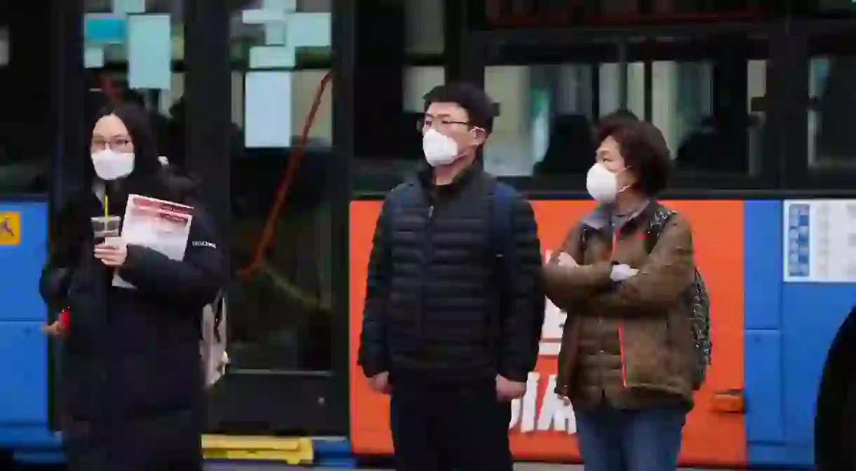 People wear masks while waiting to cross the road in Seoul, South Korea