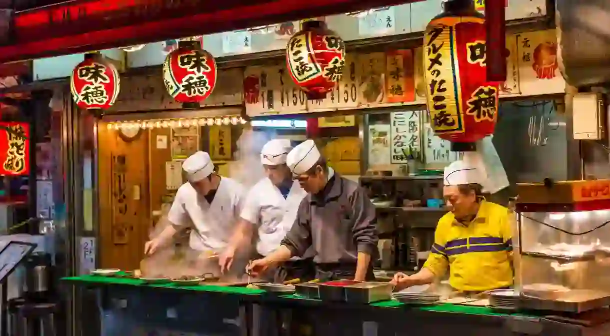 Japanese chefs prepare takoyaki and other snack foods at a stall in Osaka, Japan.