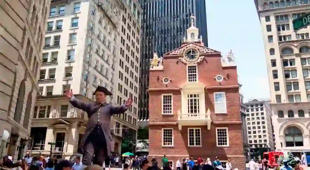 A guide in traditional costume stands in front of the Old Statehouse on the Freedom Trail in Boston