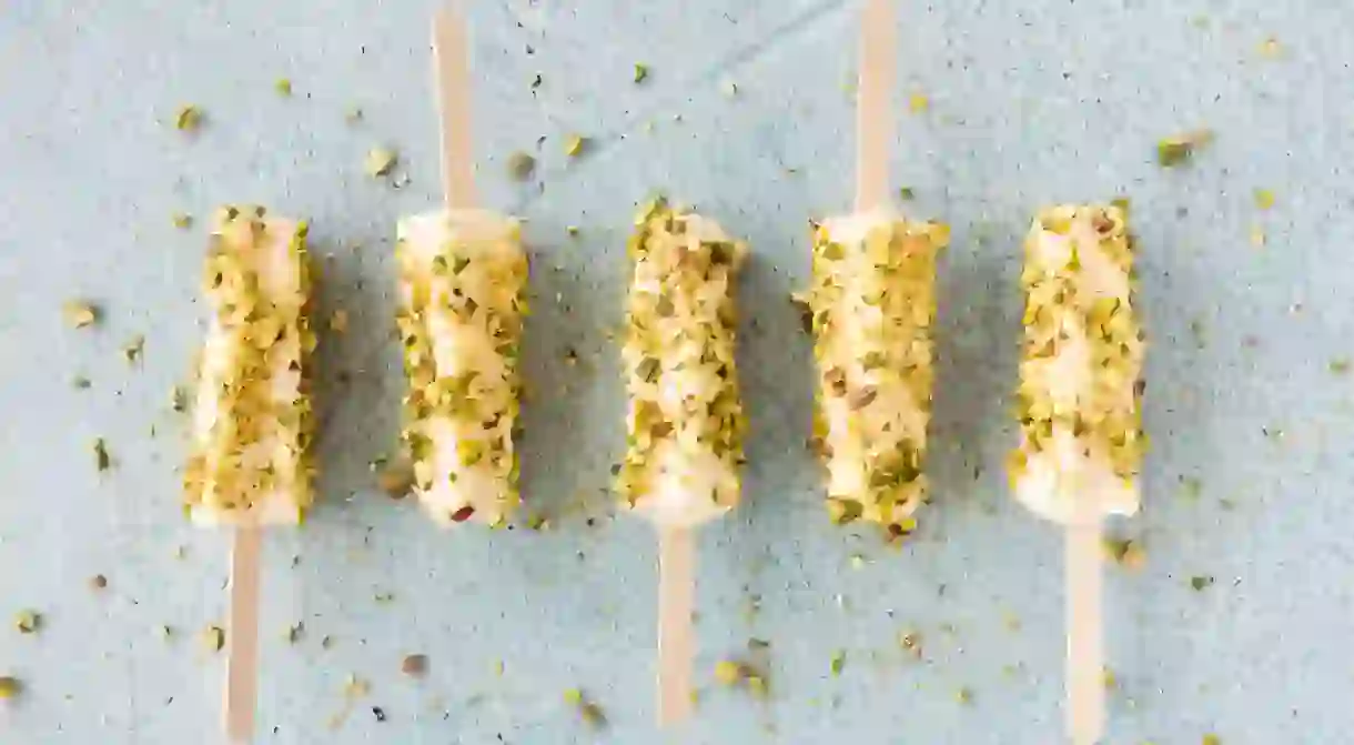 Mango and pistachio kulfi lollies on blue cement background. Top view.