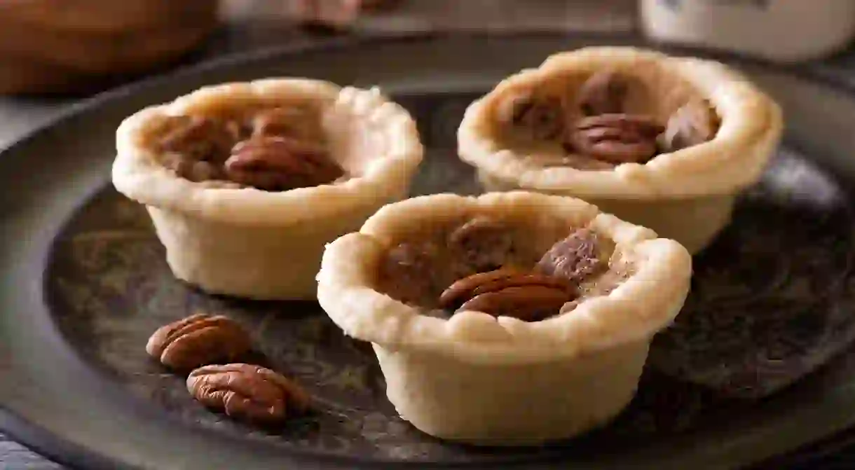 Delicious homemade mini pecan butter tarts on a rustic table top.