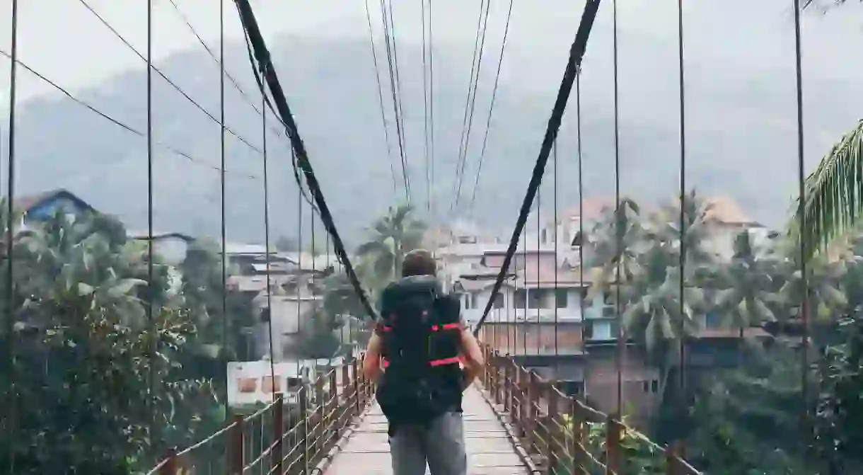 Backpacker walking towards mountain village amoing Laotian jungles in Laos