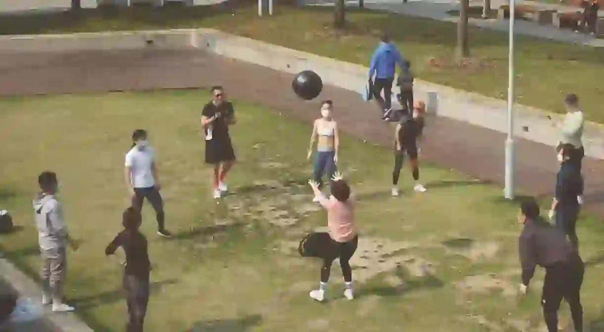 Young people take part in an outdoor fitness class, but they continue to wear masks and keep their distance from each other