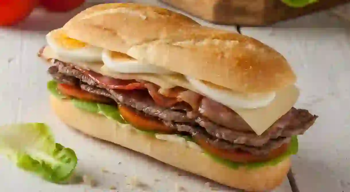 Chivito is a typical sandwich from Uruguay, often featuring lettuce, tomato, bacon, beef, fried or boiled eggs and cheese