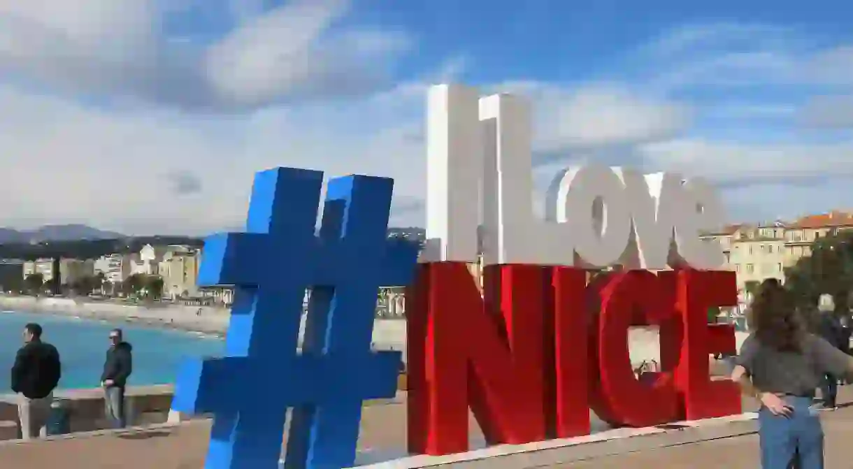 Tourists hang out and pose for selfies by the # I Love Nice slogan