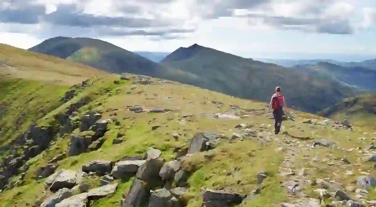 A hiker walking off Great Carrs towards the Old Man of Coniston and Dow Crag in the Lake District.