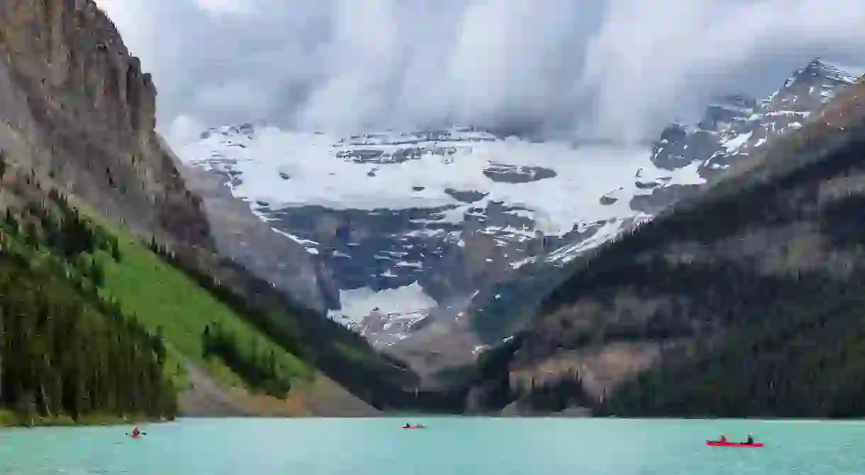 The snow-capped Rocky Mountains overlooking canoes out on Lake Louise