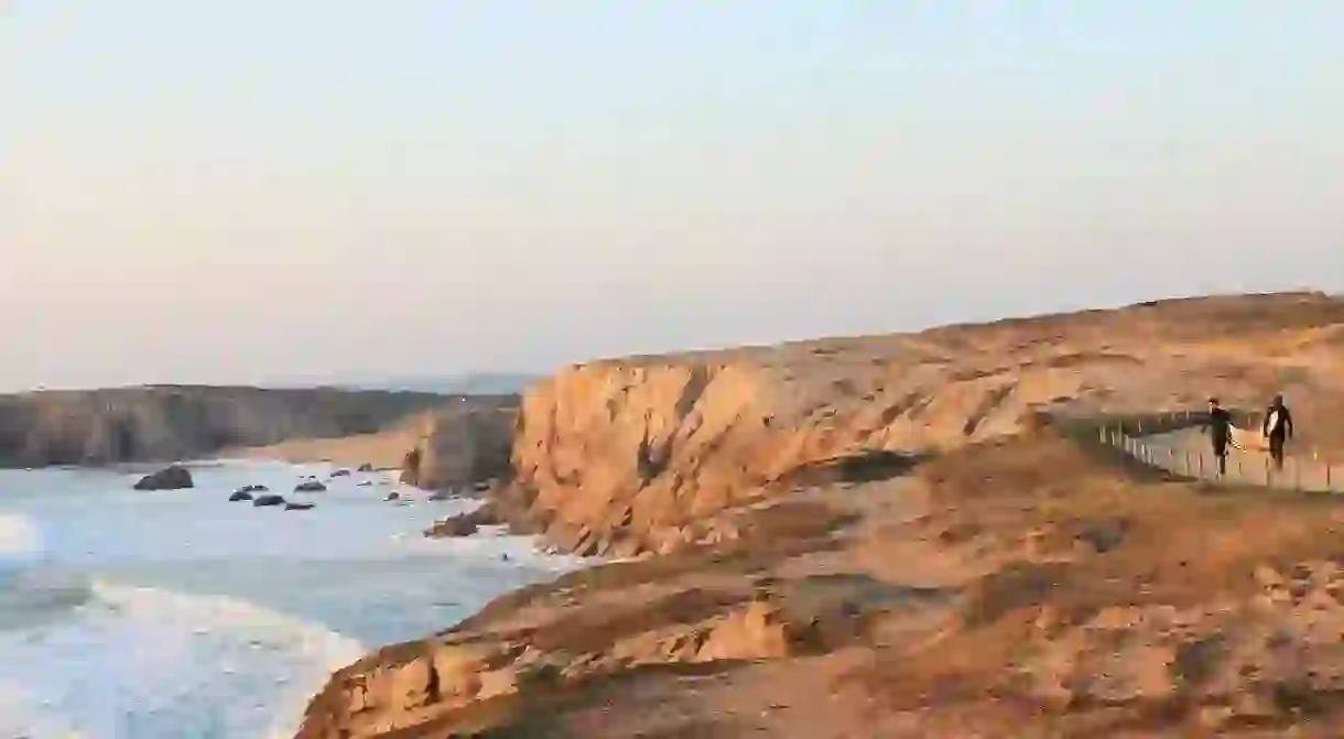 Surfers on the Cote Sauvage, in western France – a magnificent region to explore if youre looking for an adventure