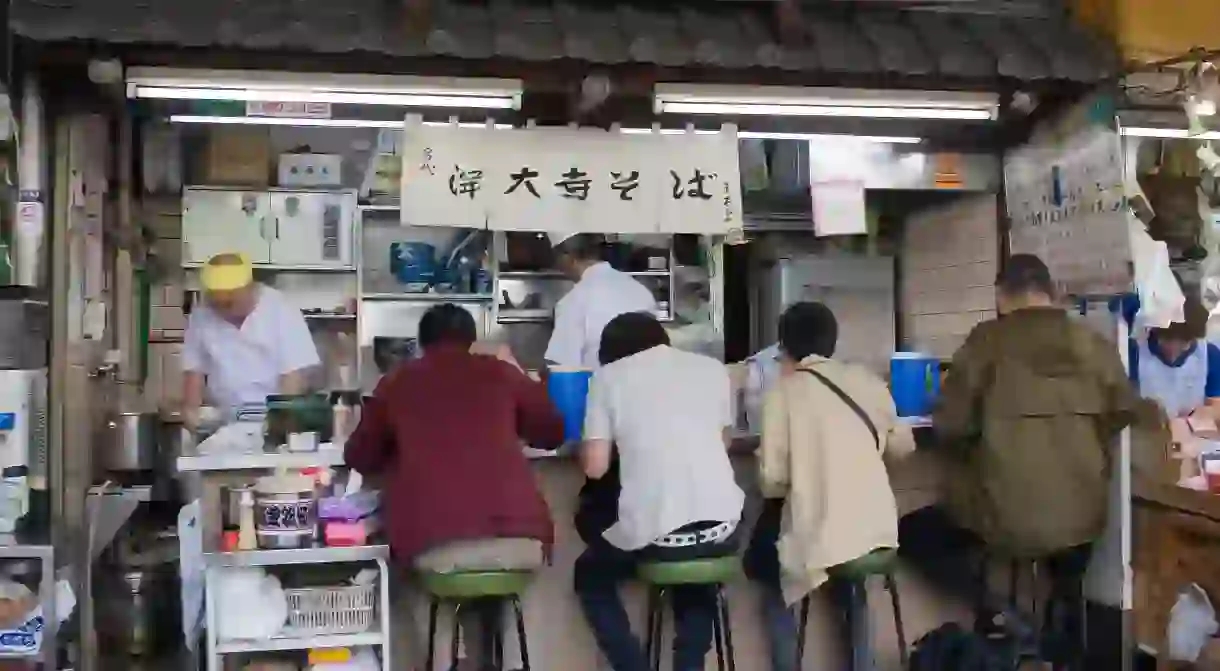 Tiny restaurant stall serving Japanese breakfast food to customers in the outer market of Tsukiji Fish Market in Tokyo.