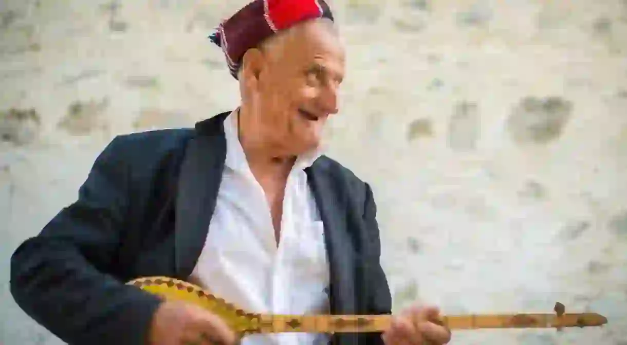 Elderly man playing a traditional cifteli instrument in Theth, Albania.