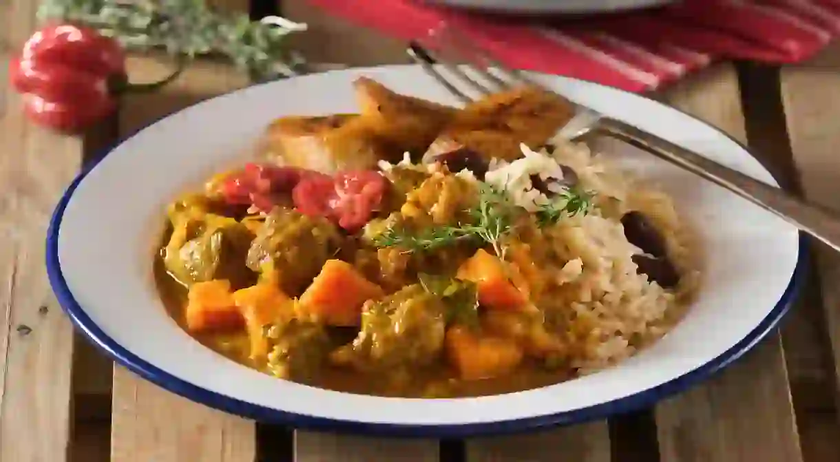 Curry goat with rice and peas is a Jamaican speciality, brimming with spices and melt-in-the-mouth, slow-cooked tender goat