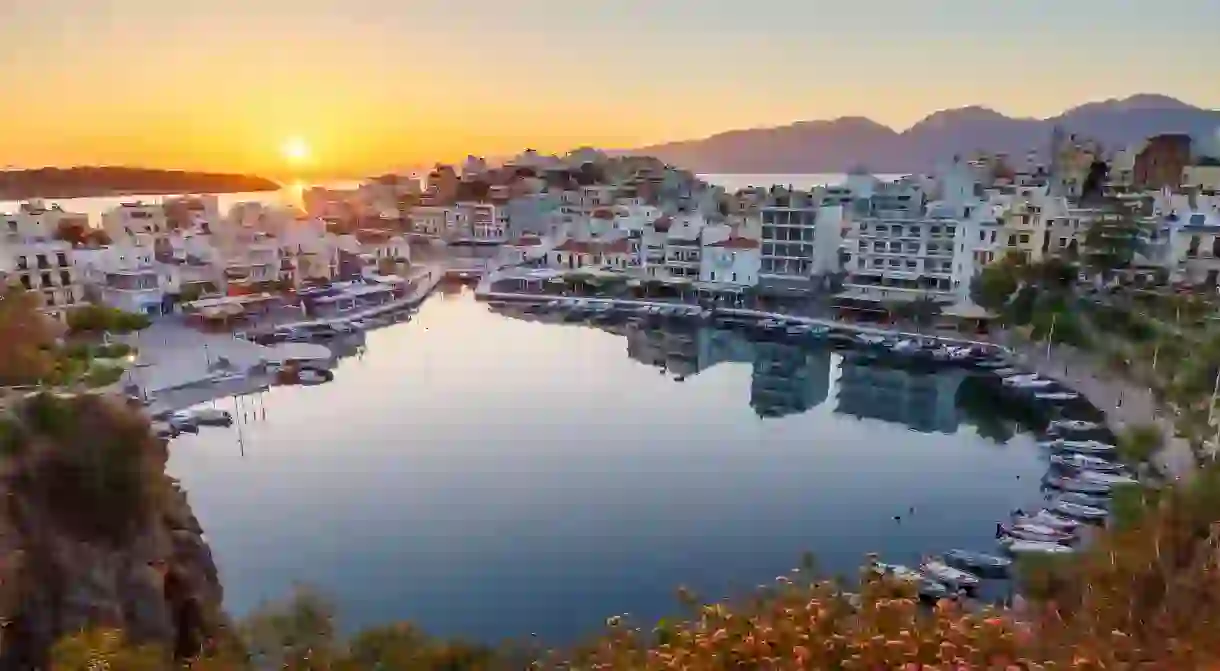 Enjoy a view of the sun setting over the stunning Agios Nikolaos and its harbor