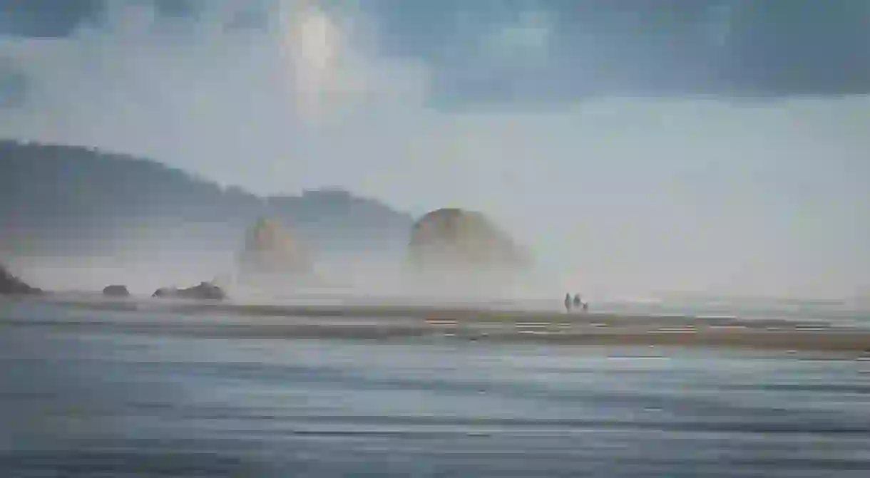 A couple walk their dog along Cannon Beach, one of Oregons most picturesque patches of sand