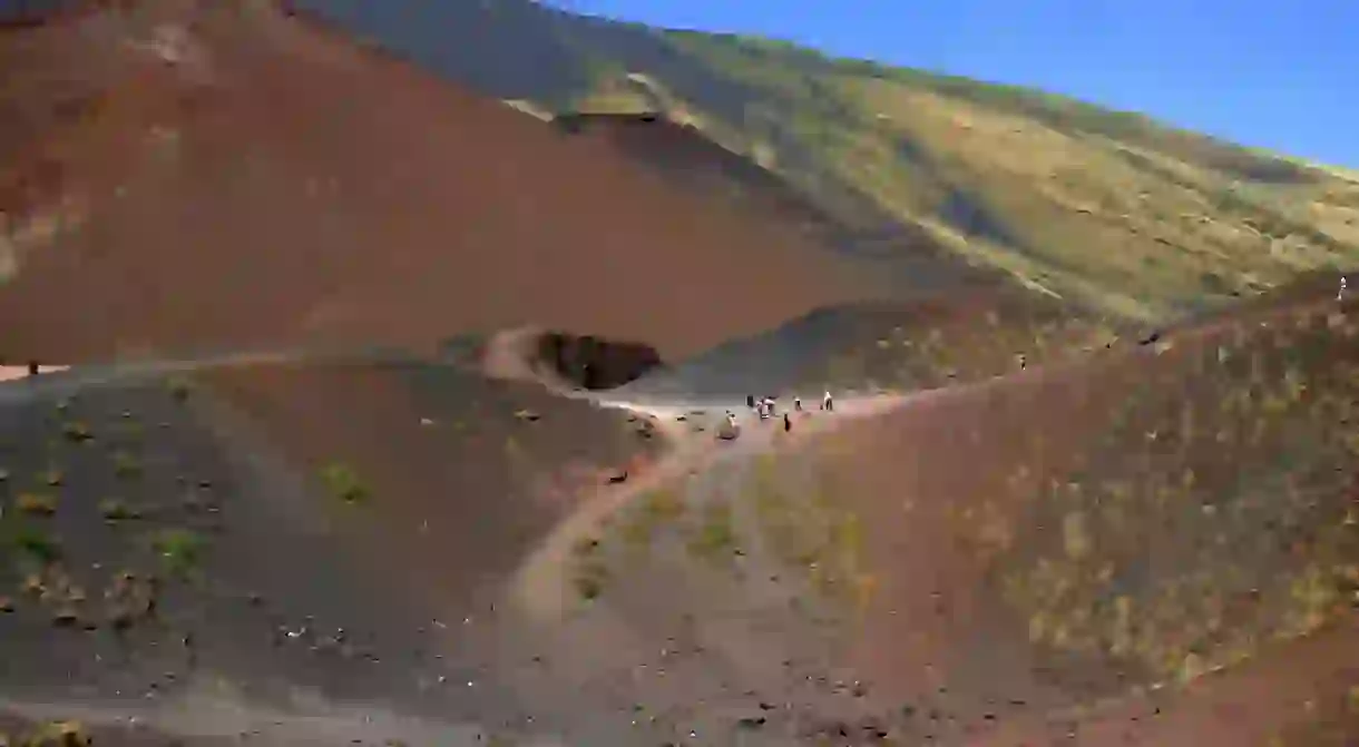 2A68E6E Tourists hiking through the volcanic landscape of The Craters Silvestri of Mount Etna (Volcano), Sicily, Italy. 8/3/2019.