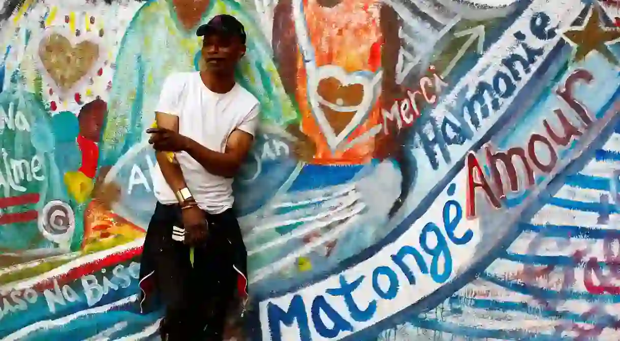 Belgian artist Gael Atumesa, originally from Congo, poses in front of his fresco in the Matongé district of Brussels