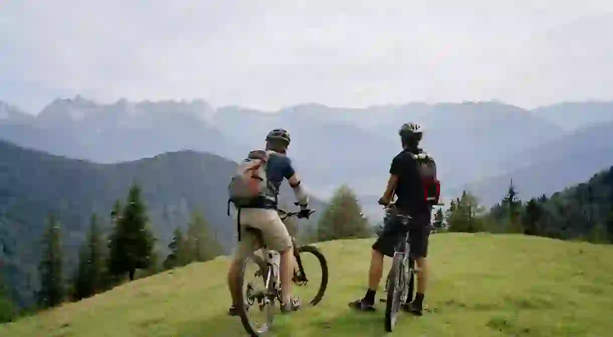 Two cyclists on the top of a hill looking at the view