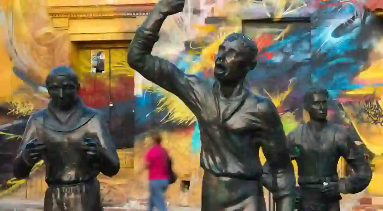 MN4EHR Wall mural behind the Statue of Pedro Romero in the colourful Plaza de la Sante­sima Trinidad, Getsemani, Cartagena, Colombia