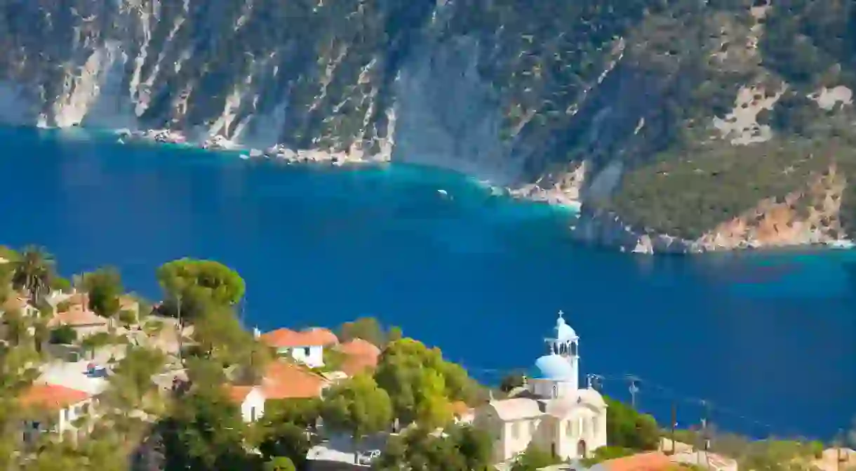 Village houses and church perched above the deep blue waters of Afales Bay, Exogi, Ithaca (aka Ithaki, Ithaka), Ionian Islands, Greece, Europe