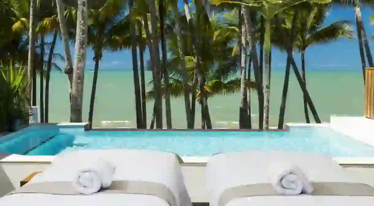 Relax poolside at the Alamanda Palm Cove, with views of palms and the ocean