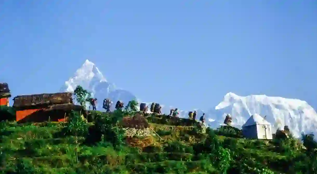 Porters carrying baskets and rucksacks with the Annapurna range in the background