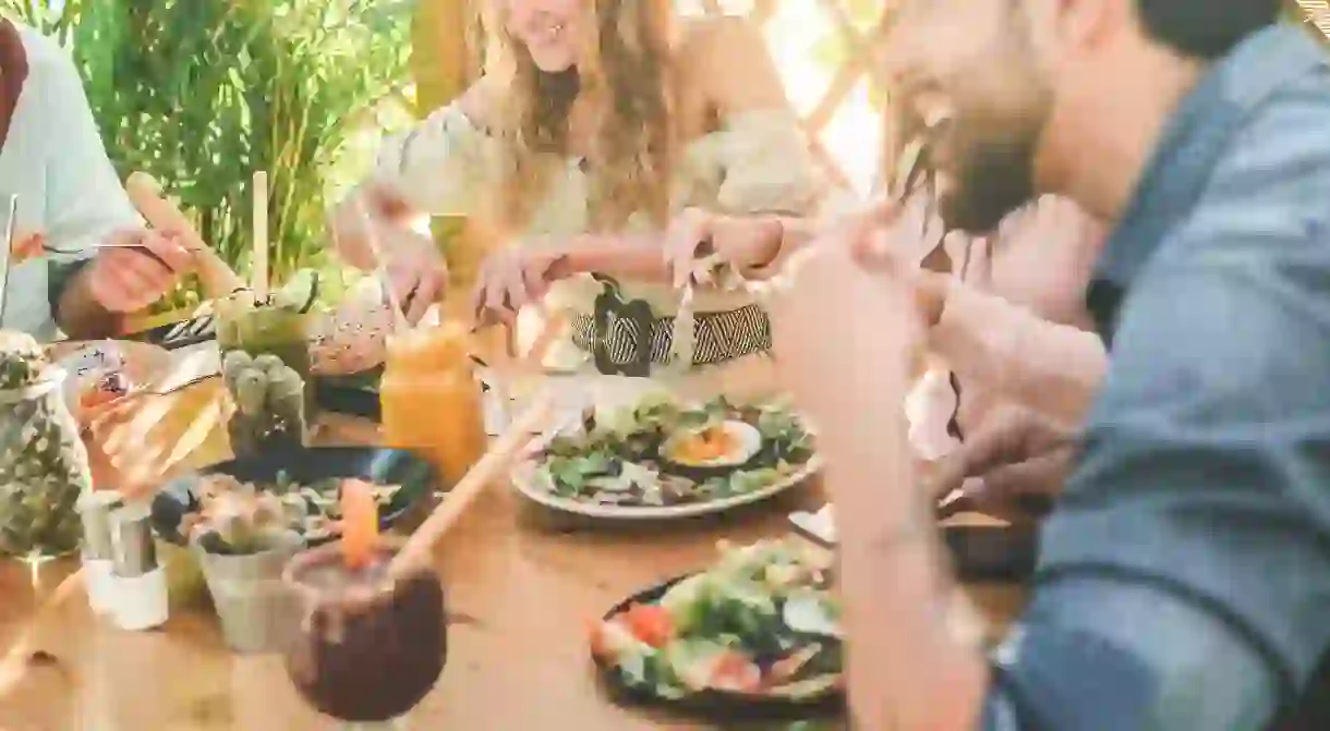 Hands view of young people eating brunch and drinking smoothies bowl with ecological straws in trendy bar restaurant - Healthy lifestyle, food trends