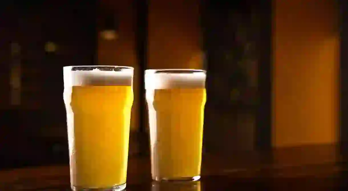 2C69MFM Order beer at pub. Glasses of ale on table in interior of dark pub 2C69MFM_