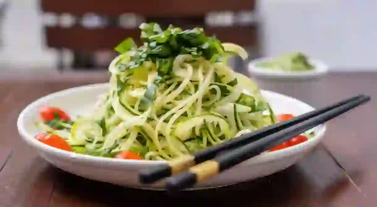 2C5YW78 Noodles of spiralized zucchini, cucumber, cherry tomato, garlic in a creamy pesto from avocado. Raw food for vegetarian. Close up