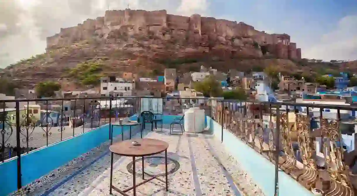 Rooftop cafe with view to Mehrangarh fort on the hill at cloudy sky in Jodhpur Blue city, Rajasthan, India