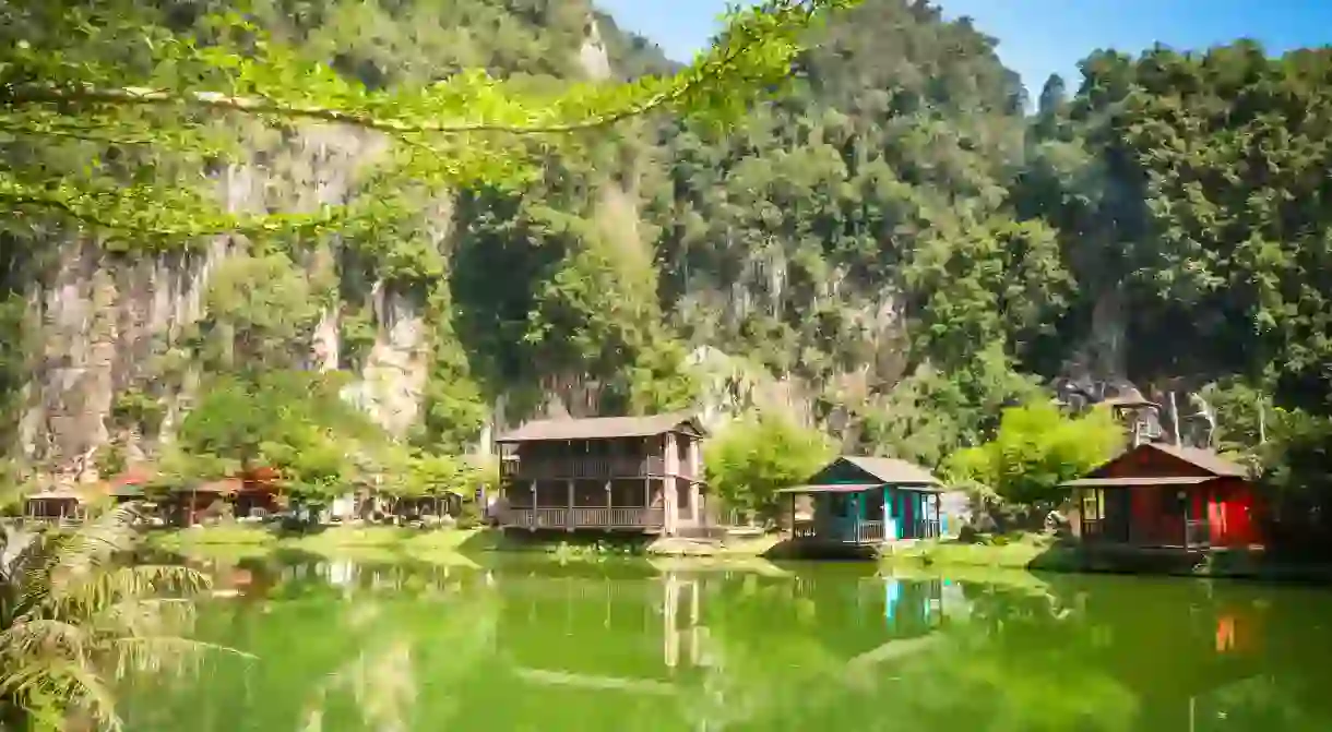 Water reflections of wooden houses with limestones on the background in the countryside of Ipoh city, Perak, Malaysia