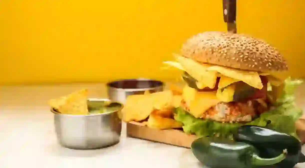 Tasty burger with nachos and guacamole on table