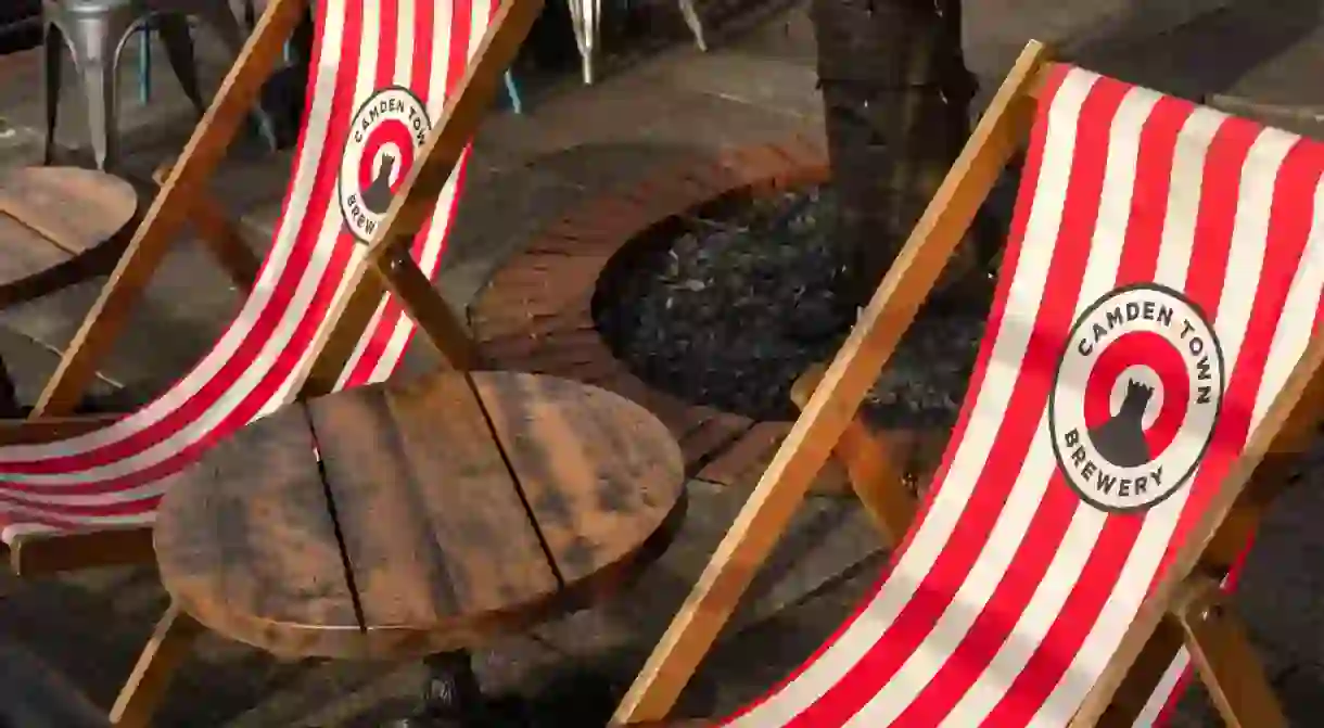 Camden town brewery logo on red and white deck chairs or deckchars and wooden table in the Anchor Pub garden on the South Bank London