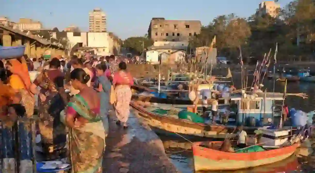 In early morning light, fishing boats are seen anchored at Sassoon Docks, a fishing harbor in Colaba, Mumbai, India, fish buyers standing on the pier