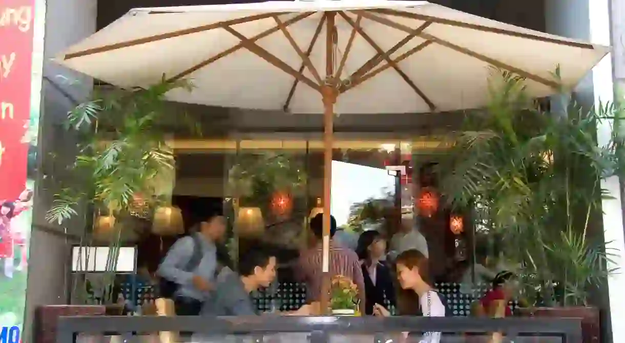 Modern Vietnamese couple eat lunch at a sidewalk cafe in Ho Chi Minh City Vietnam