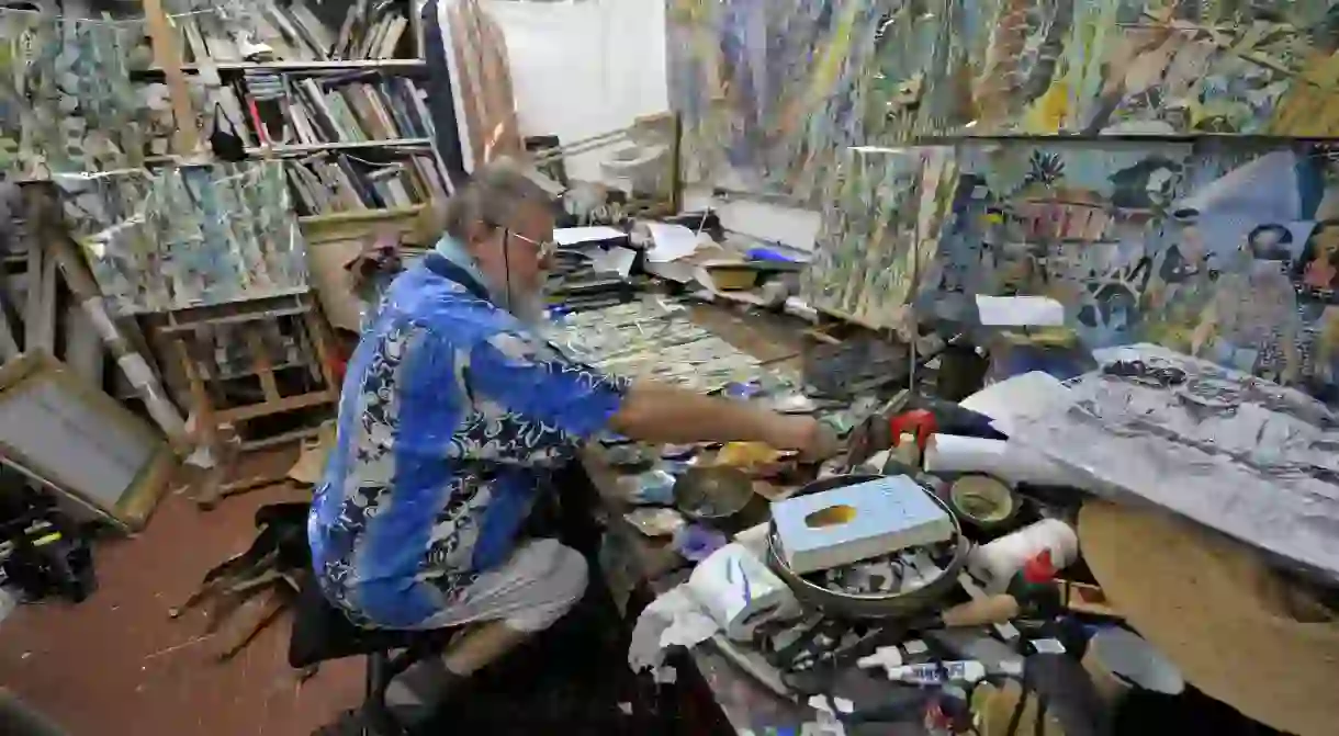 Painter Michael Adams sitting in his studio at Anse Poules Bleues, Mahé Island, Seychelles