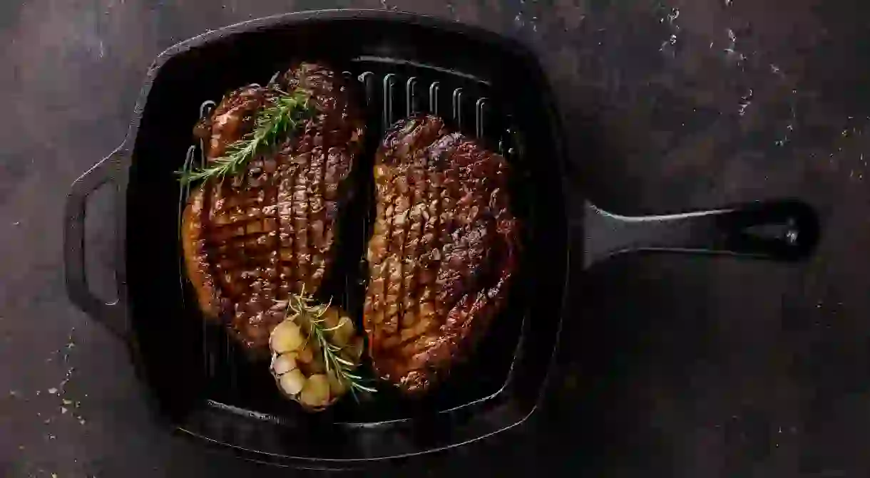 Grilled Black Angus Steak Striploin on frying cast iron Grill pan on dark background