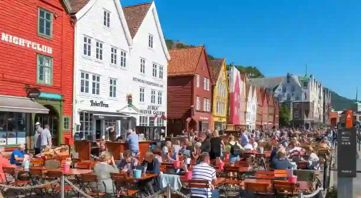 Bergen, Norway. Cafes and bars in front of traditional wooden buildings in historic Bryggen district, Vagen harbour, Bergen, Norway