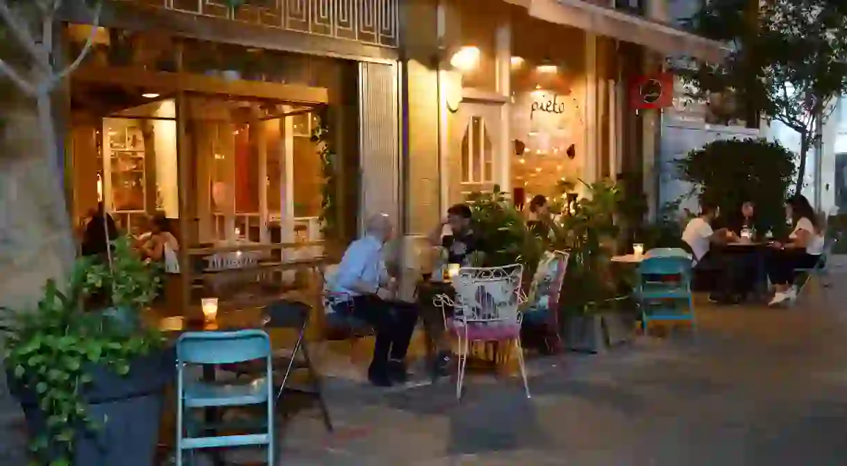 2DC72DK Tables, chairs and customers on pavement outside Pietos restaurant in old town Nicosia and seeing inside through door, Cyprus