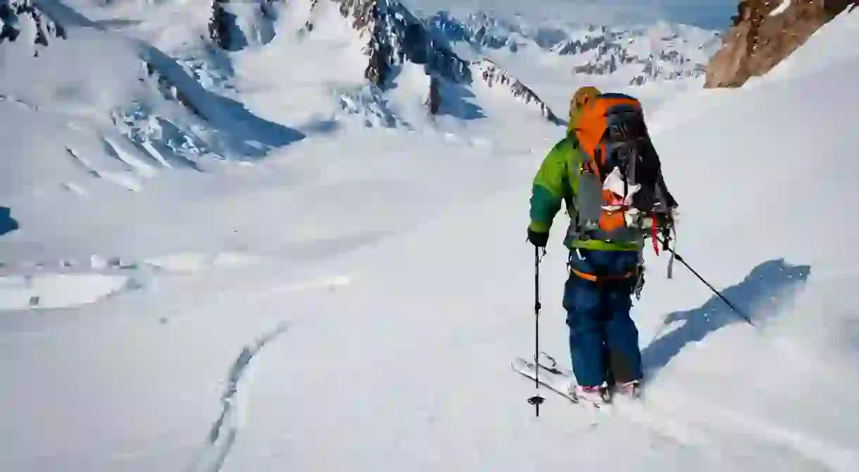 Backpacker skiing Trimble Glacier with Martin Peak and Denali in the distance, Tordrillo Mountains in Southcentral Alaska