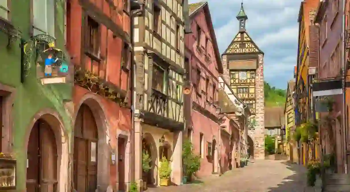 Central street of Riquewihr village with colorful traditional half-timbered french houses and Dolder Tower, Alsace, France