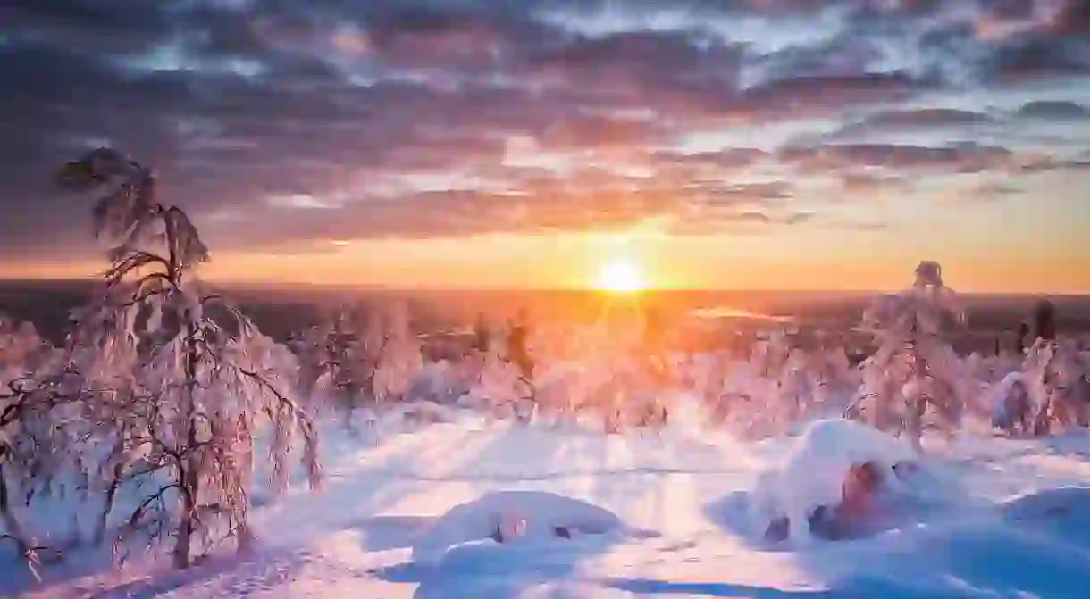 Panoramic view of beautiful winter wonderland scenery in scenic golden evening light at sunset with clouds in Scandinavia, northern Europe