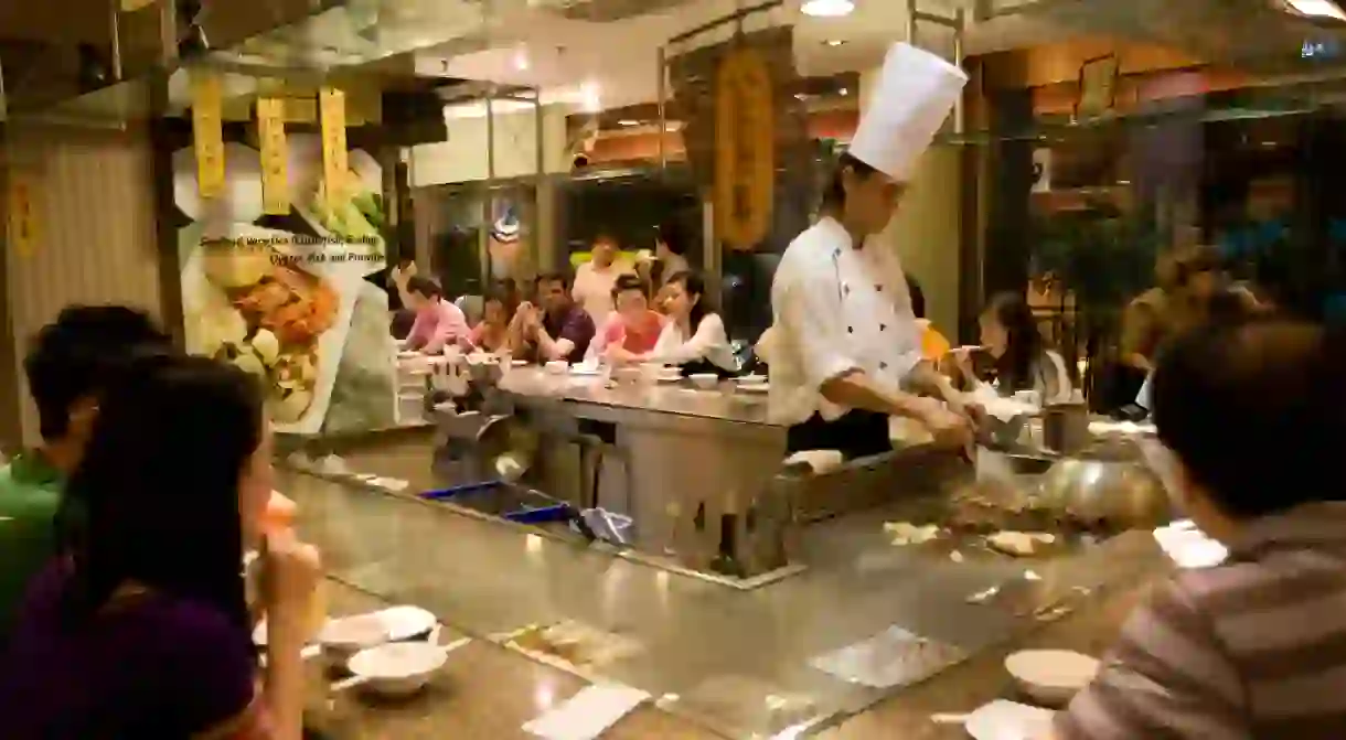 Chef preparing a meal surrounded by diners in a restaurant, Singapore