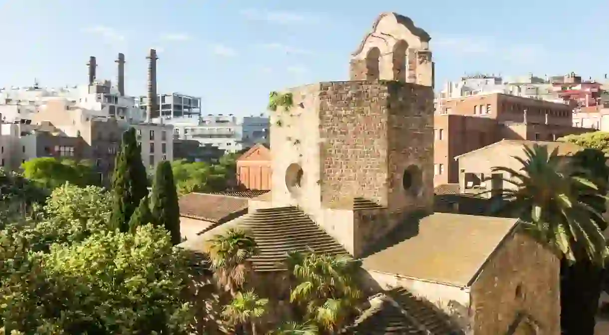 View of the Raval neighborhood in Barcelona: Sant Pau del Camp church, the oldest church in the city of Barcelona, and the three chimneys of the Paralelo avenue. Spain