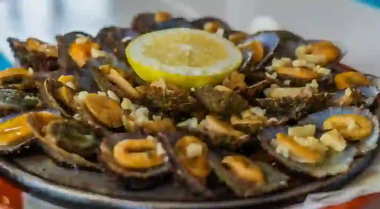 2D9BM5P tasty seafood - grilled limpets served with lemon. Lapas grelhadas. Azores traditional dish and a typical snack of the Canary Islands. Grilled Limpets