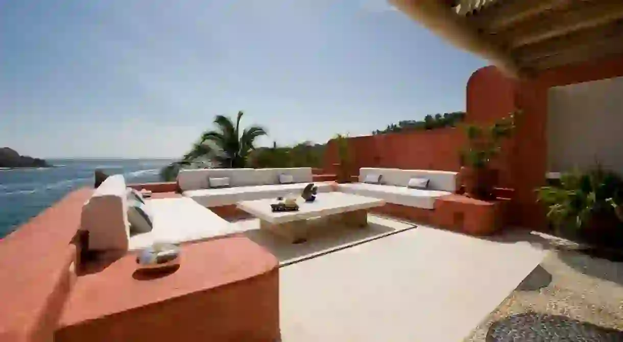 A stylish sea-view seating area at Casa Carioca in Careyes with three built-in sofas, a central coffee table and potted plants