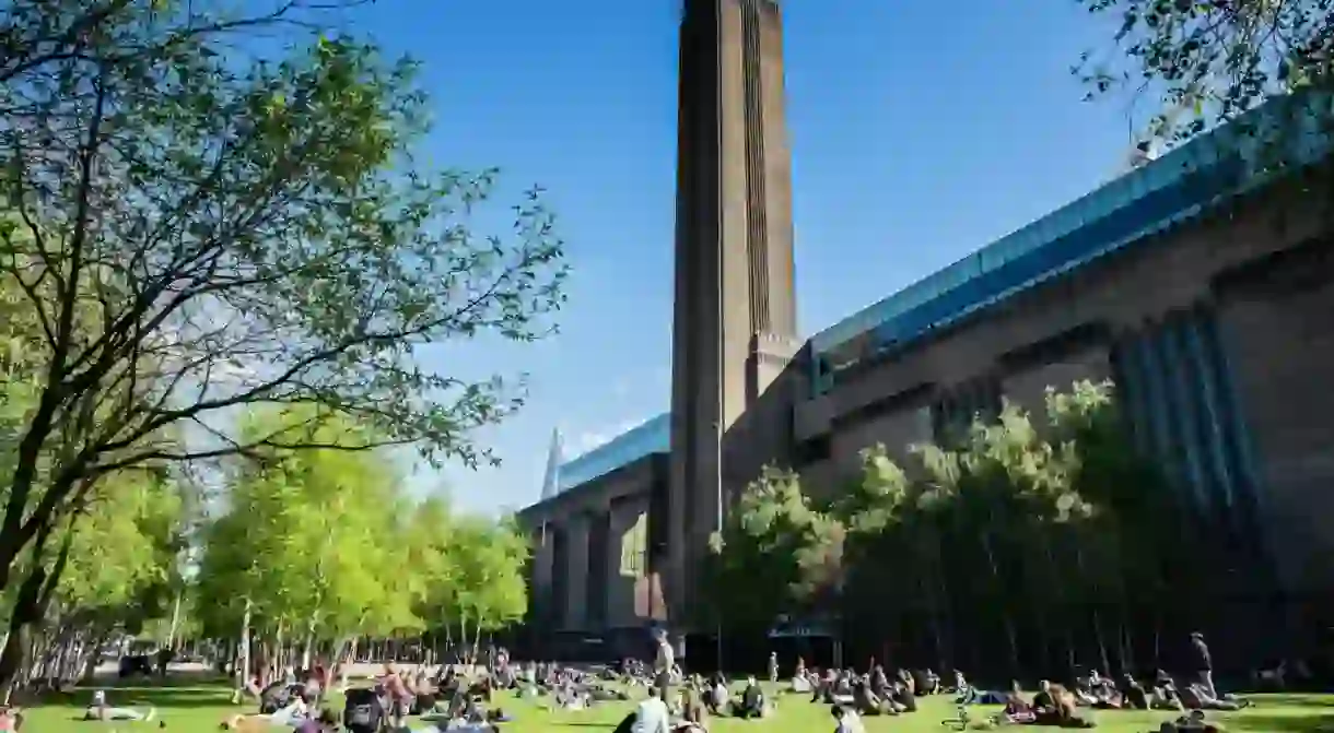 People relaxing in park in front of Tate Modern art gallery in London