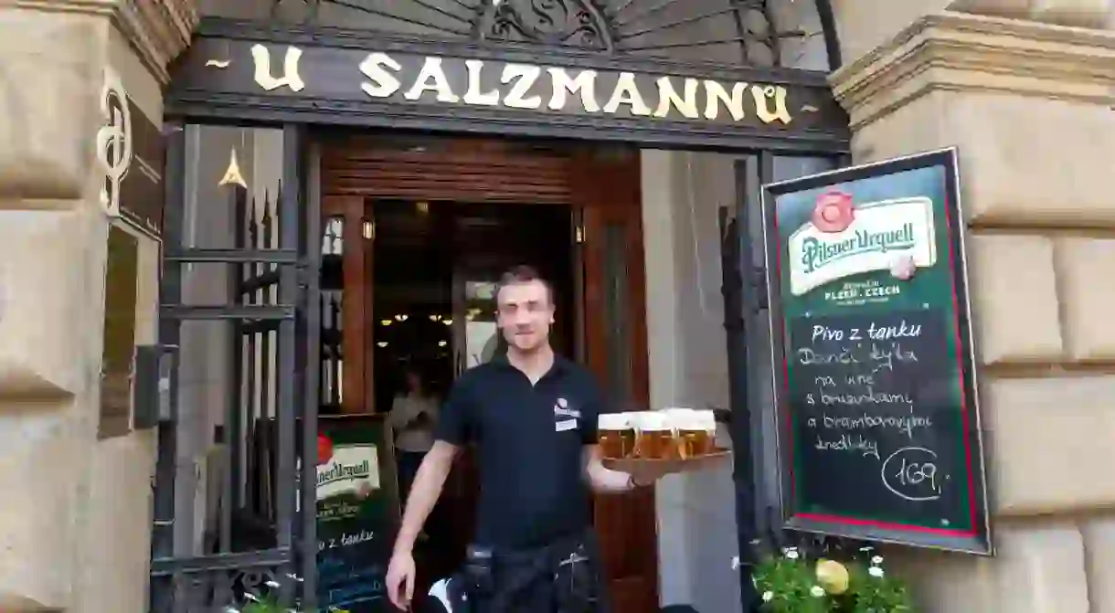 Waiter serving Pilsener beer in Pilsen Famous restaurant U Salzmannu