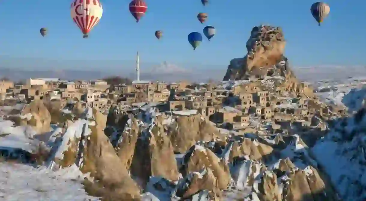 Hot Air Ballooning over Ortahisar Fortress. Cappadocia, Nevsehir,Central Anatolia.Cappadocia has unreal amazing landscape which makes Balloon flights one of worlds the top 3. The spectacular surrealistic landscapes combined with excellent flying conditions allow the balloons to gently drift over and between fairy chimneys, pigeon houses hewn into the unique rock formations, orchards and vineyards through impressive valleys, each with distinctive rock formations, colors and features and then float up over rippled ravines for breathtaking views over the region.