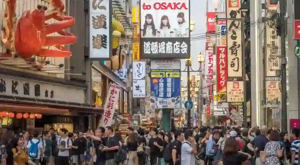 Welcome to Osaka: a shopping street with a giant crab in the Dotonbori area of Osaka, Japan.