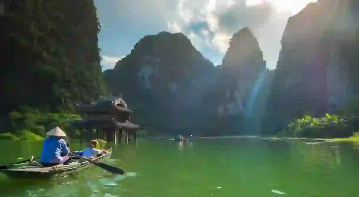 Foreign tourists ride local boat in Trang An landscape complex, Ninh Binh, Hanoi, Vietnam