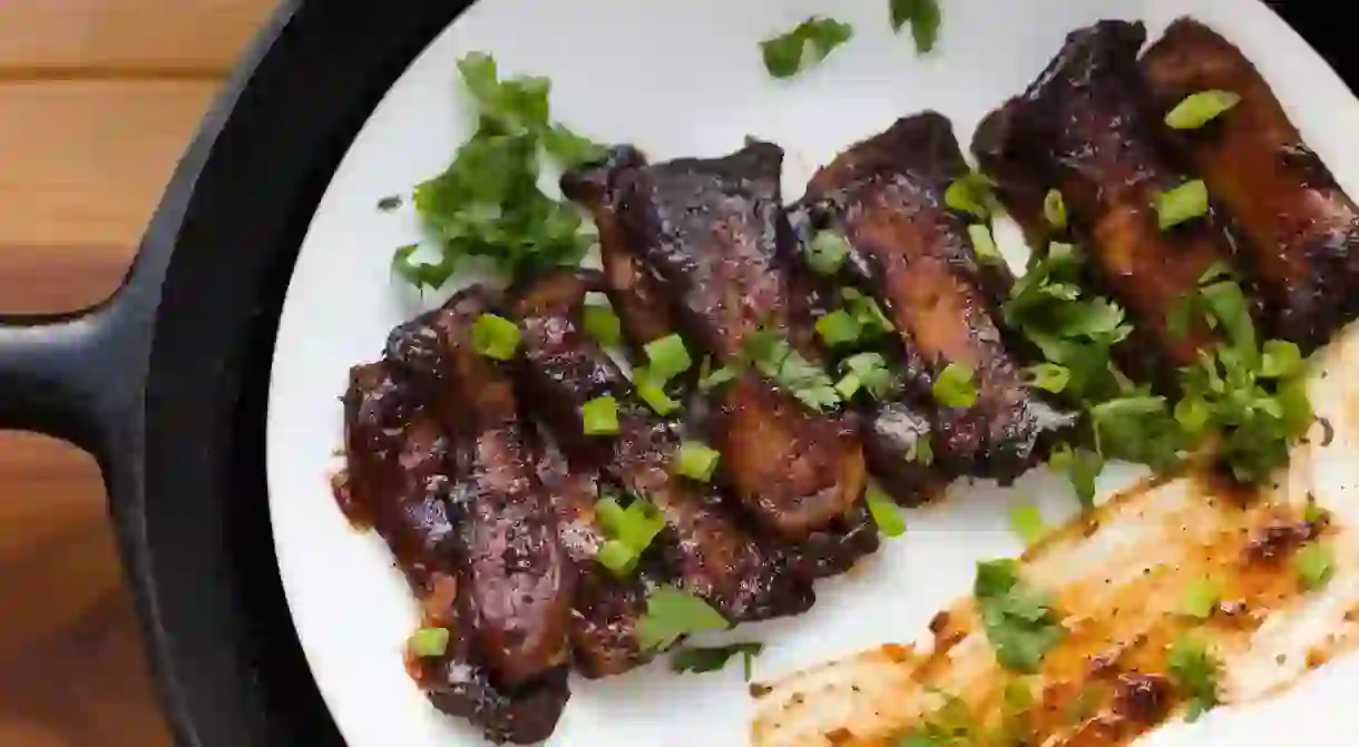 Vegan Mushroom BBQ RIbs garnished with green onions, bbq sauce, and cilantro.